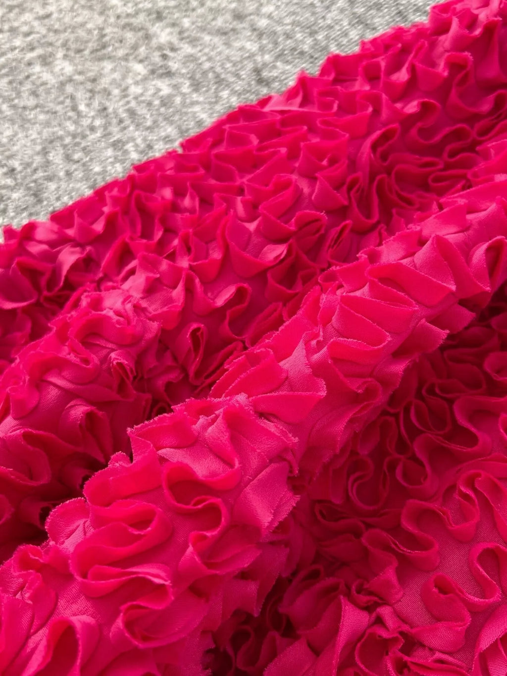 Close-up of raised bright pink ruffled flower details on skirt fabric.