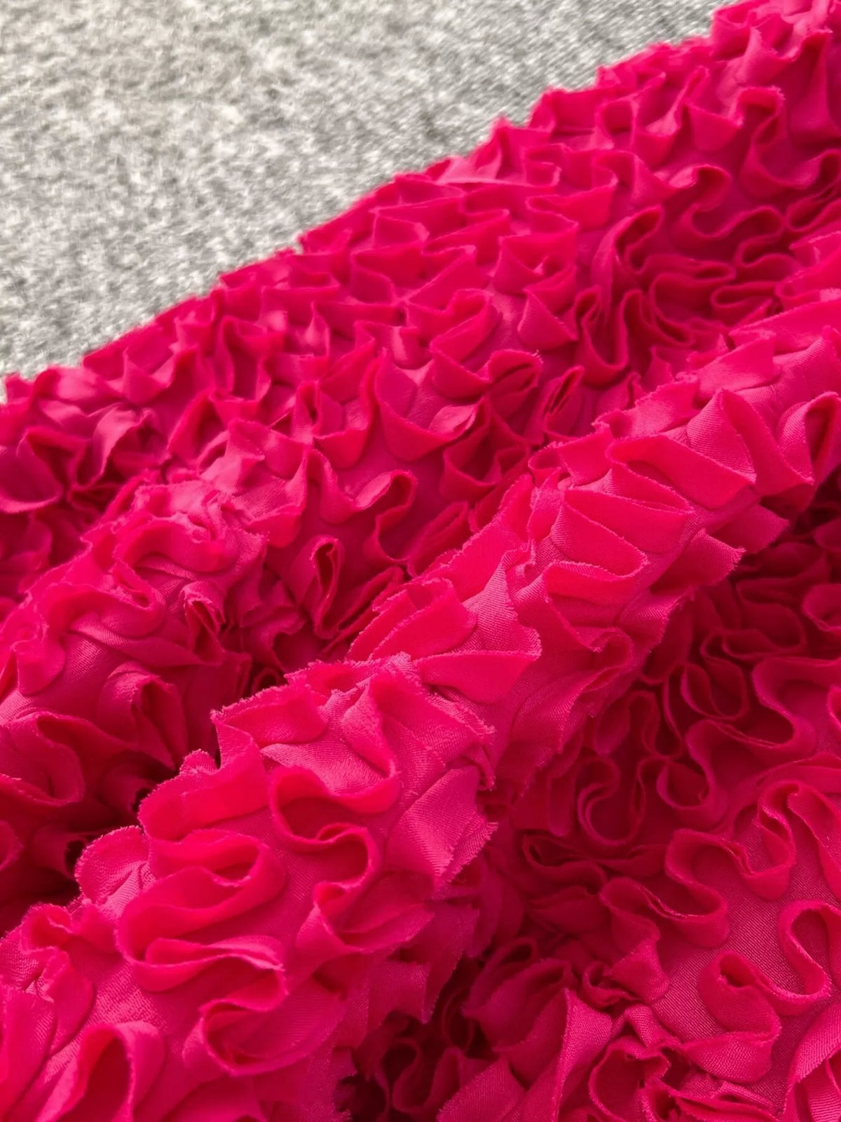 Close-up of raised bright pink ruffled flower details on skirt fabric.