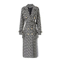 Black and white geometric double-breasted trench coat with gold buttons and a waist tie, front view.