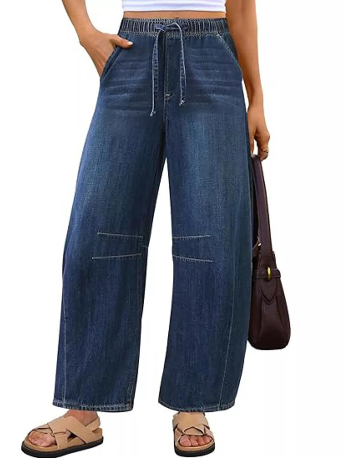Model wearing dark blue wide-leg jeans with a drawstring elastic waist and curved leg seams, front view.