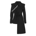 Black fitted blazer with silver fringe across one lapel and a long asymmetric hem, front view.