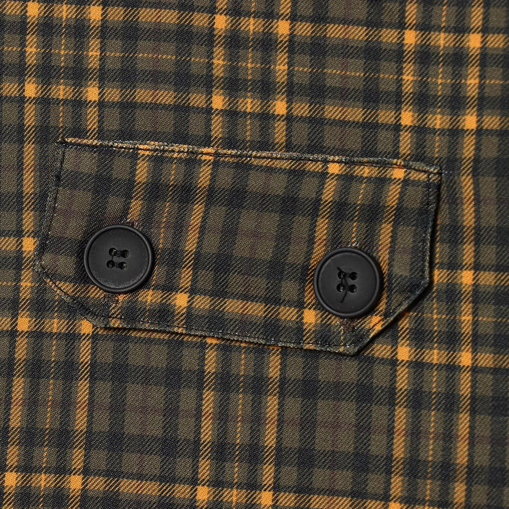 Close-up of a two-button flap pocket and gold plaid stripes on dark olive skirt fabric.