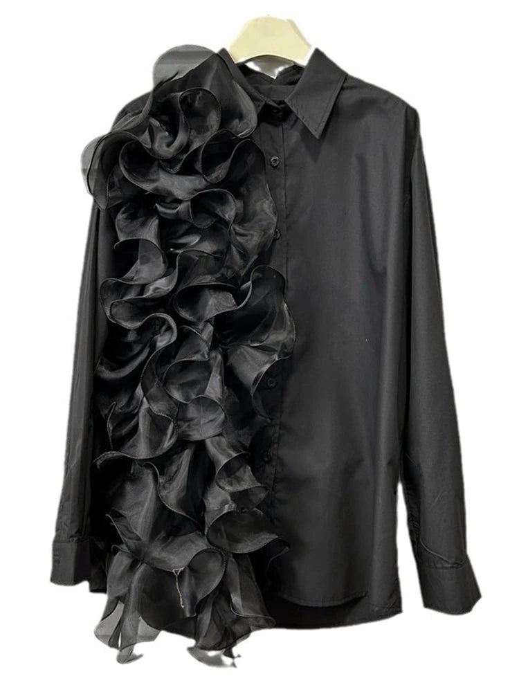Black button-front blouse with long sleeves and asymmetric cascading ruffles, hanging front view.