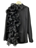 Black button-front blouse with long sleeves and asymmetric cascading ruffles, hanging front view.
