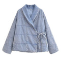 Light blue quilted wrap jacket with a shawl collar, horizontal stitching, and side ties, front view.