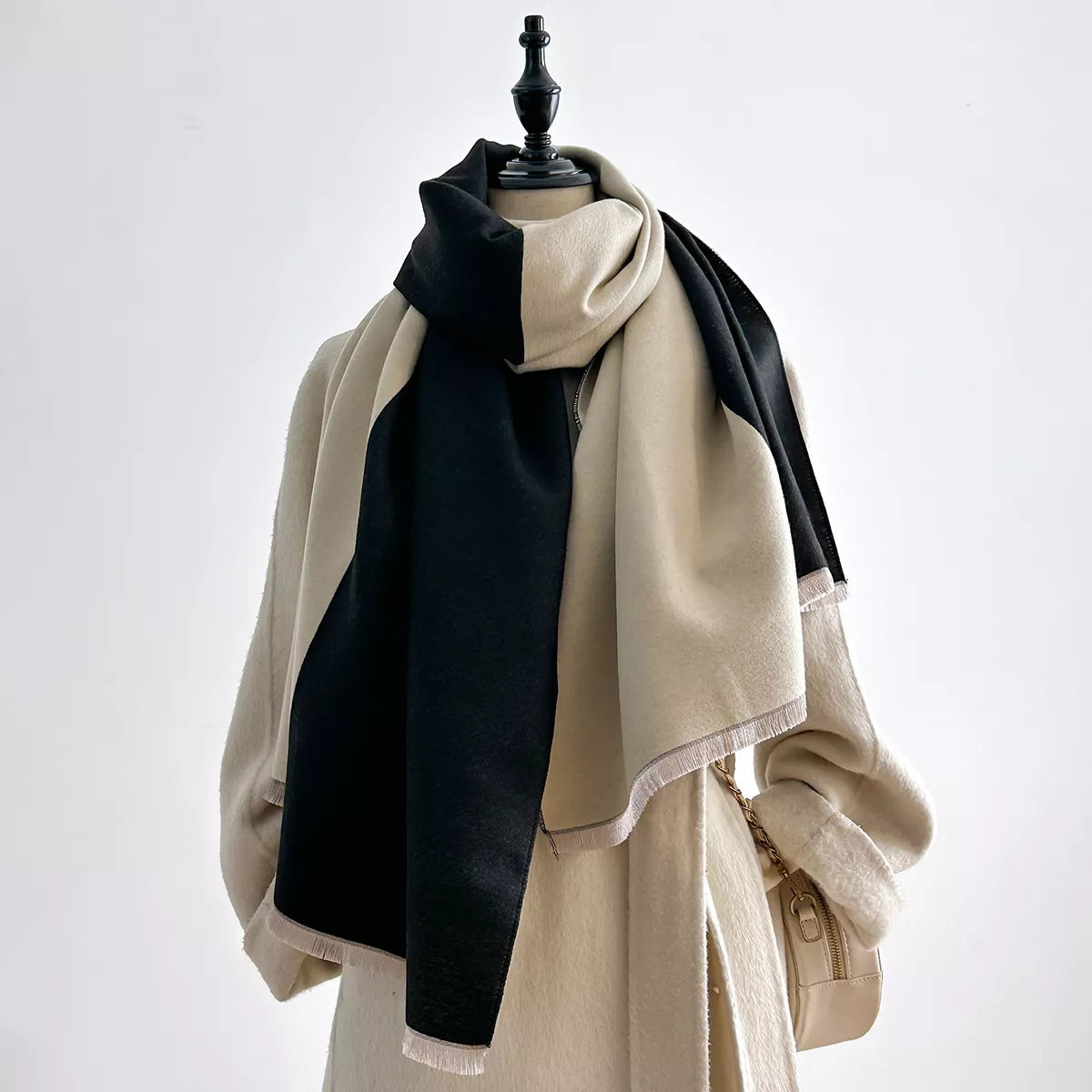 Black and cream two-tone scarf with short fringe draped around a mannequin's neck.