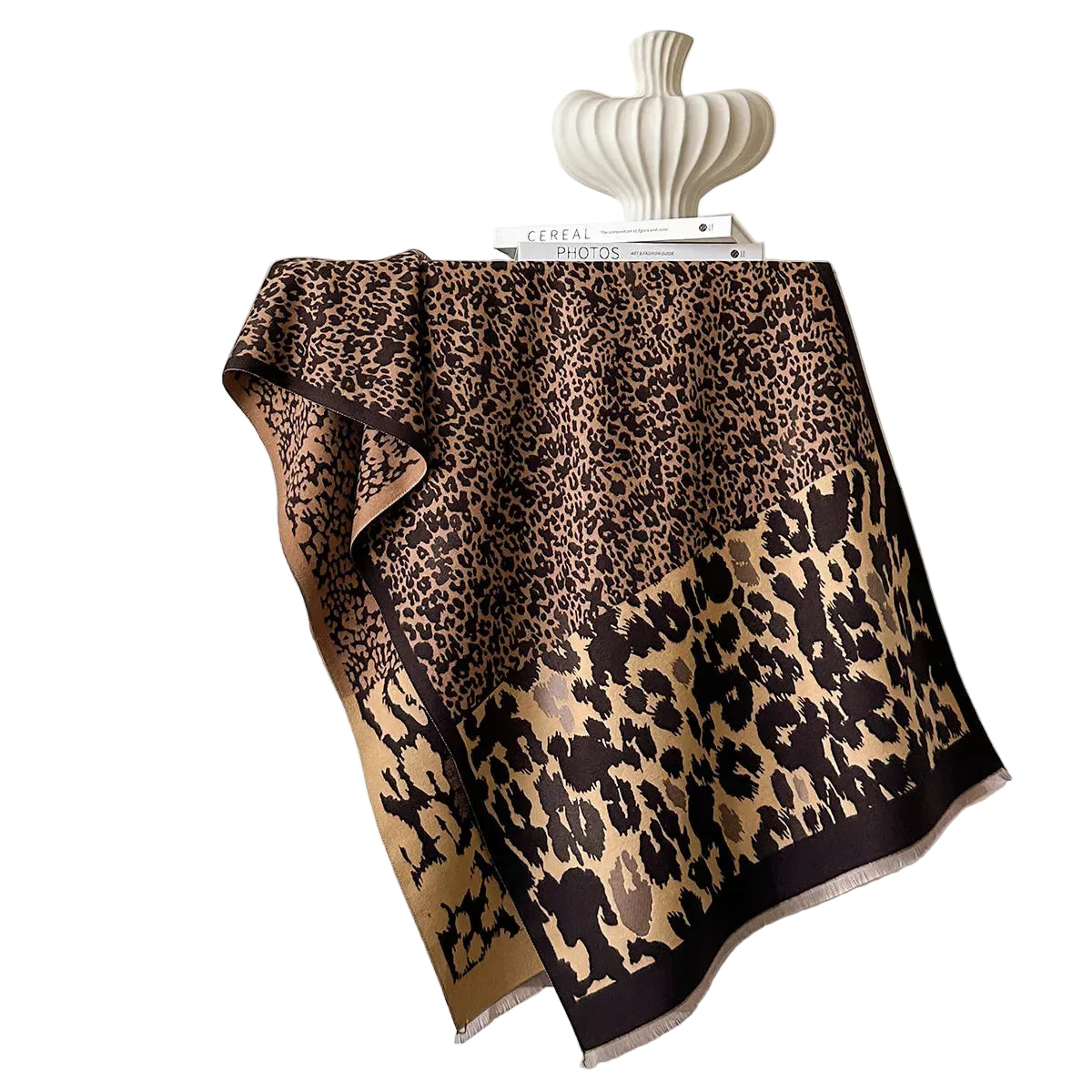 Tan and black mixed-scale leopard-print scarf spread over a chair, showing its border and short fringe.