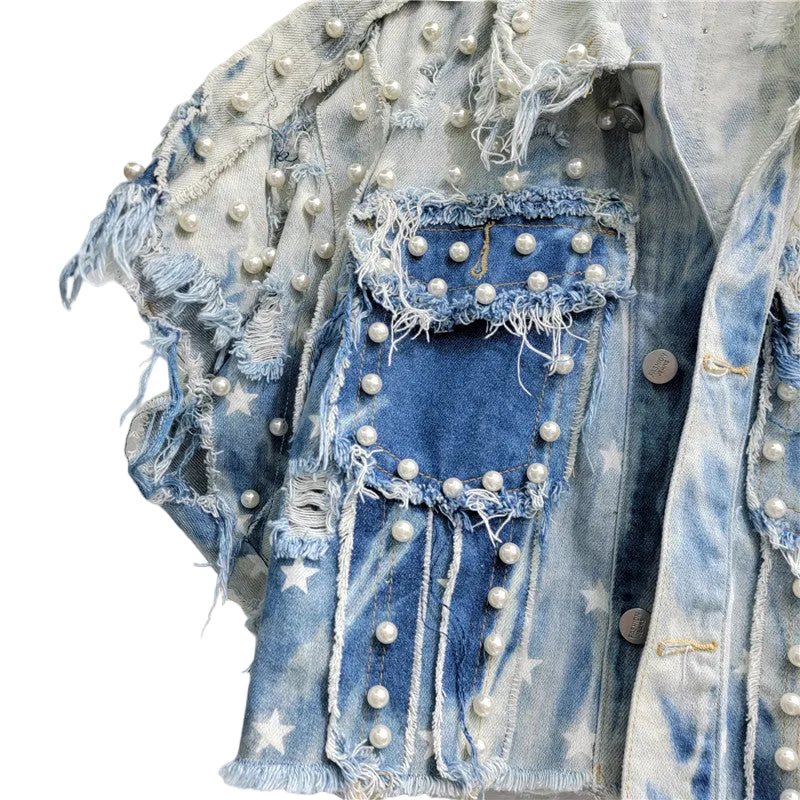 Close-up of a frayed denim chest pocket with pearl-like studs and white star print.
