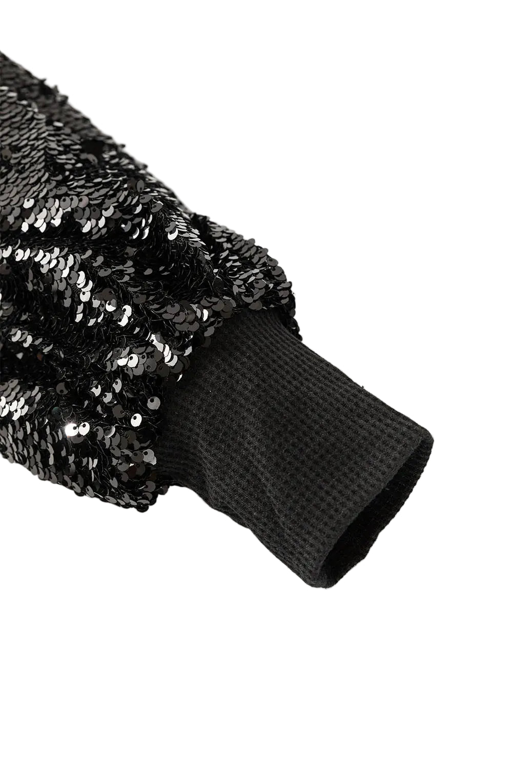 Close-up of a black sequined blouse sleeve and plain ribbed cuff.
