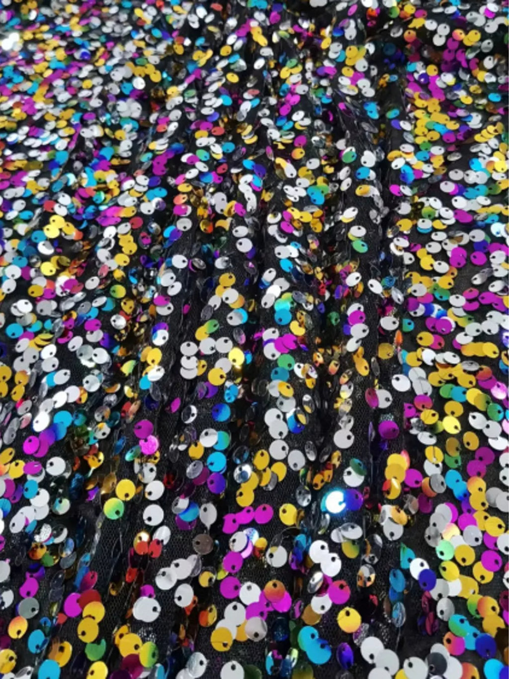 Close-up of pink, blue, gold, and silver sequins on black skirt fabric.