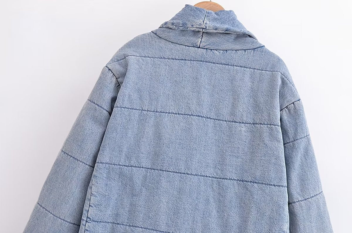 Back detail of a light blue quilted jacket showing the shawl collar and horizontal stitching.