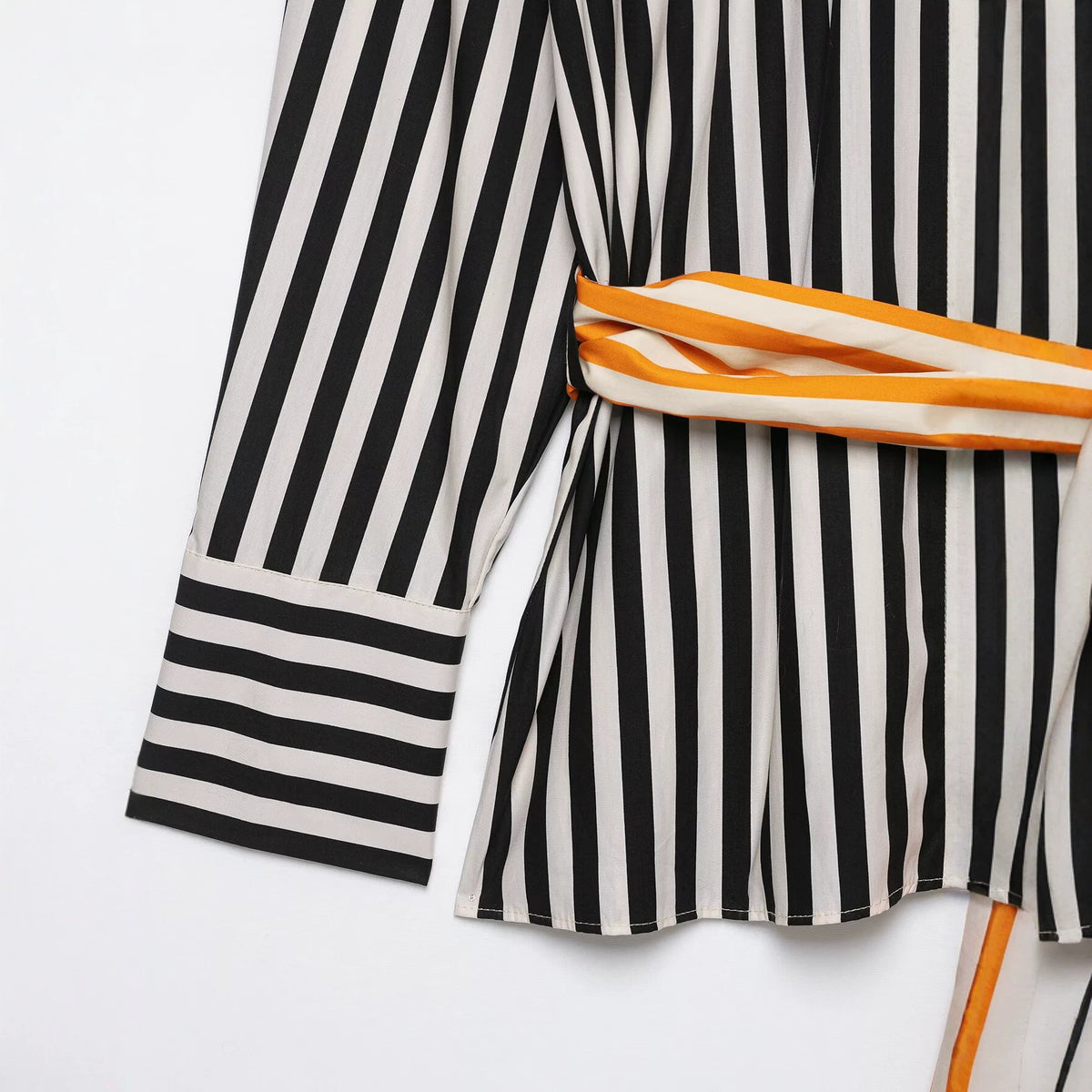 Close-up of the striped shirt's cuff, hem, and orange and white waist tie.