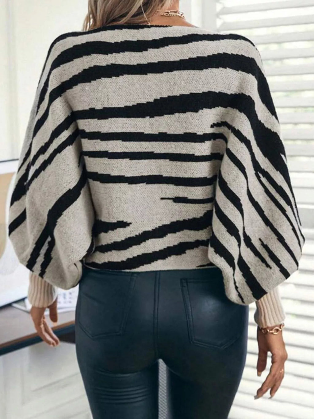 Back view of a black and cream striped sweater with long balloon sleeves and ribbed cuffs.
