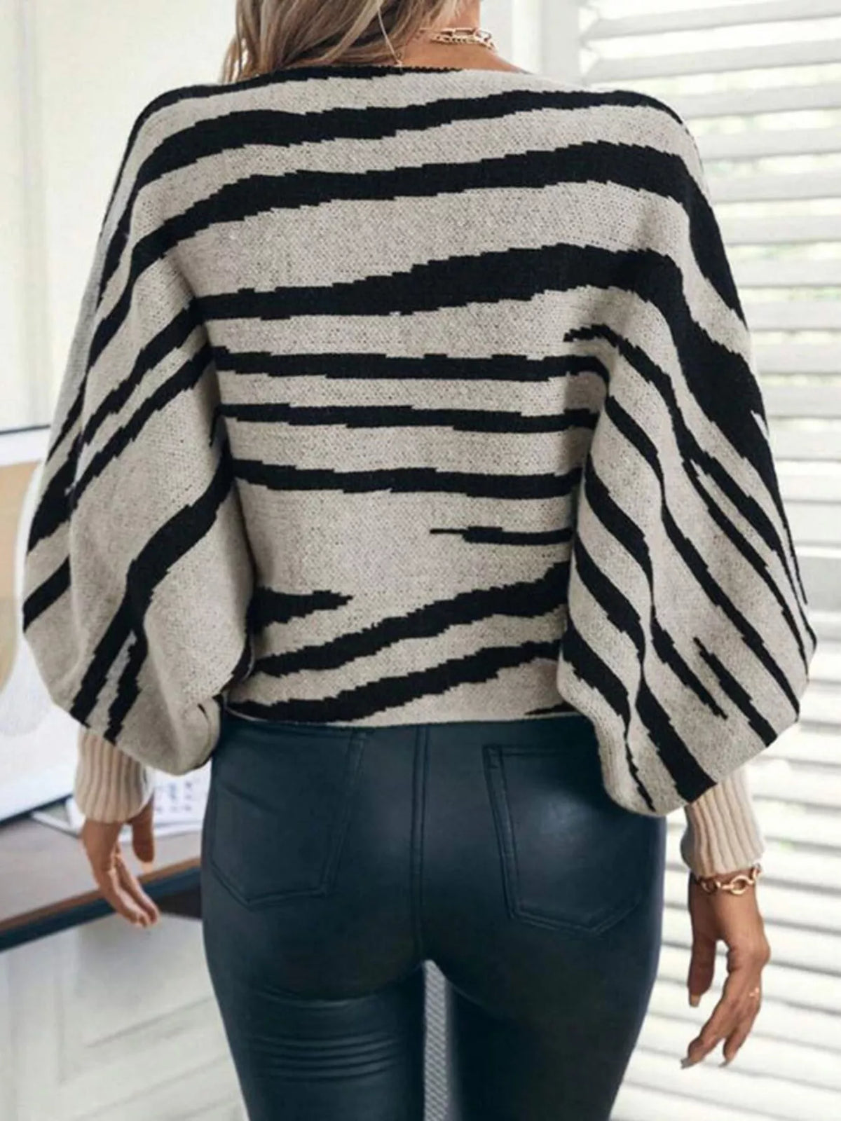 Back view of a black and cream striped sweater with long balloon sleeves and ribbed cuffs.