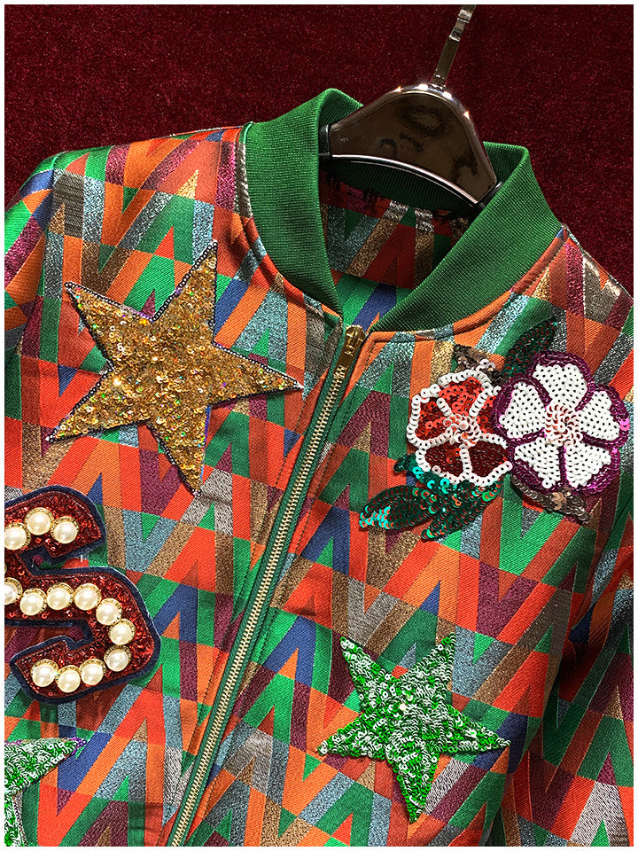 Close-up of the bomber jacket's green collar, zipper, gold sequin star, and floral patches.