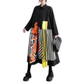 Model wearing a black button-front shirt dress with striped skirt and orange and yellow panels, front view.