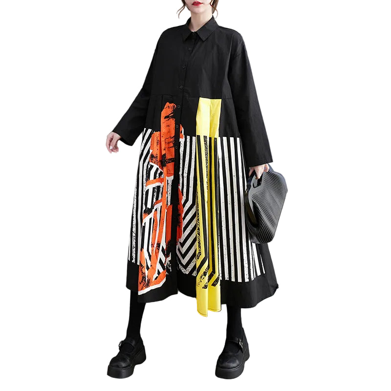 Model wearing a black button-front shirt dress with striped skirt and orange and yellow panels, front view.