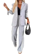 Model wearing a light gray blazer and wide-leg pants with white striped sleeve and leg panels, front view.
