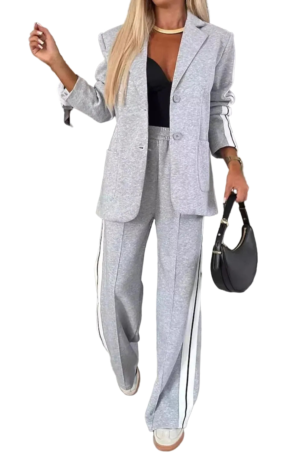 Model wearing a light gray blazer and wide-leg pants with white striped sleeve and leg panels, front view.