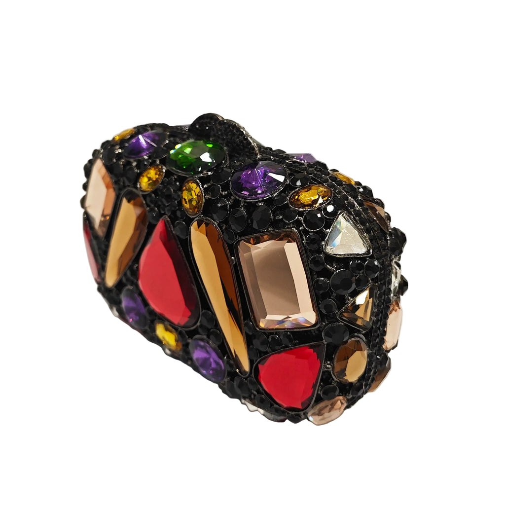 Angled close-up of a black oval clutch covered in colorful faceted stones and small black stones.