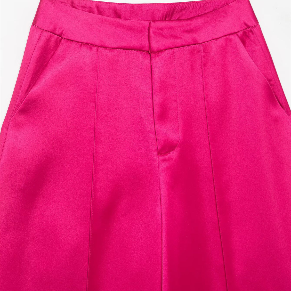 Close-up of the waistband, front pleats, and pockets on bright pink satin-look pants.