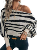 Angled view of a black and cream striped sweater worn off one shoulder, with long balloon sleeves.