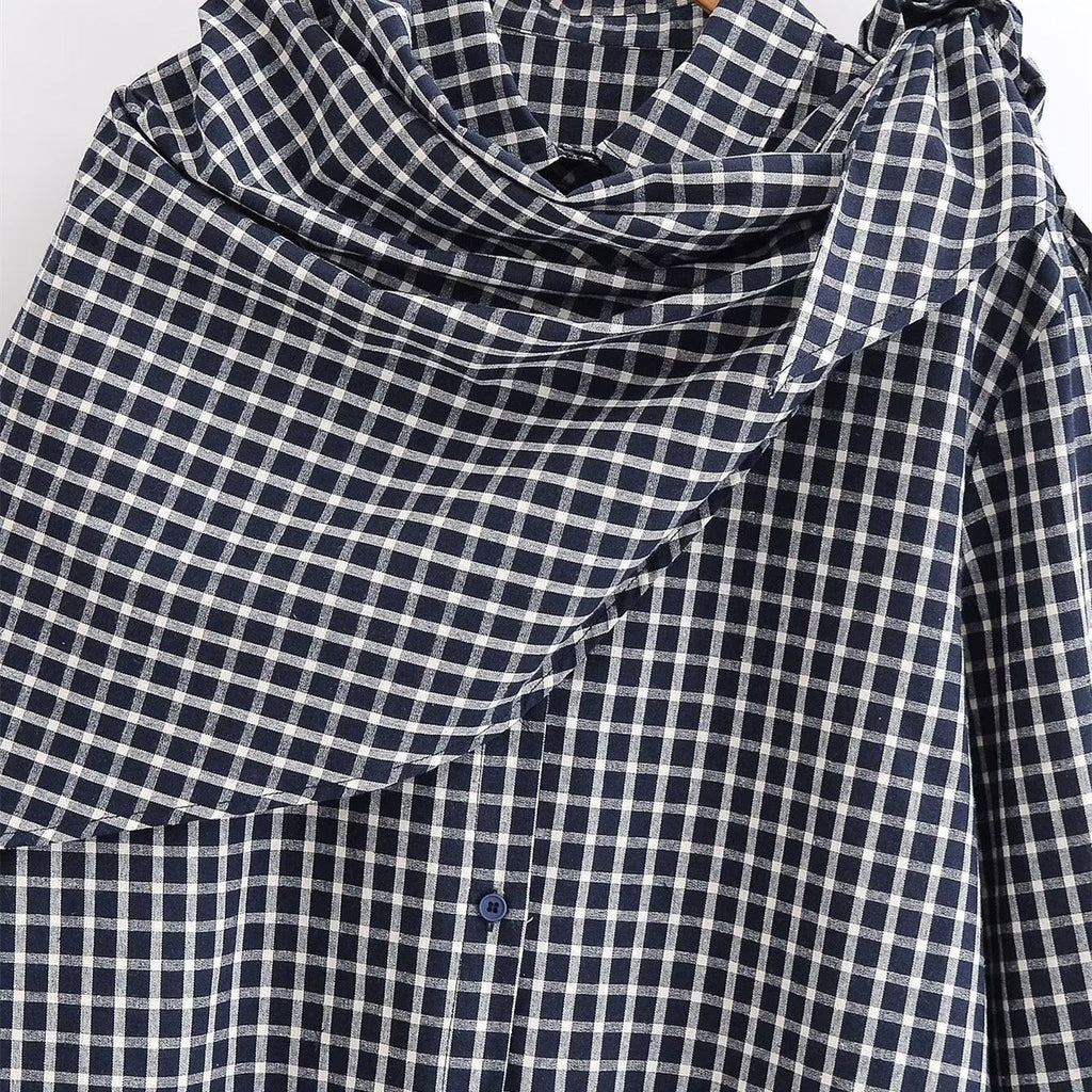 Close-up of the black and white checked shirt's collar and matching knotted scarf.