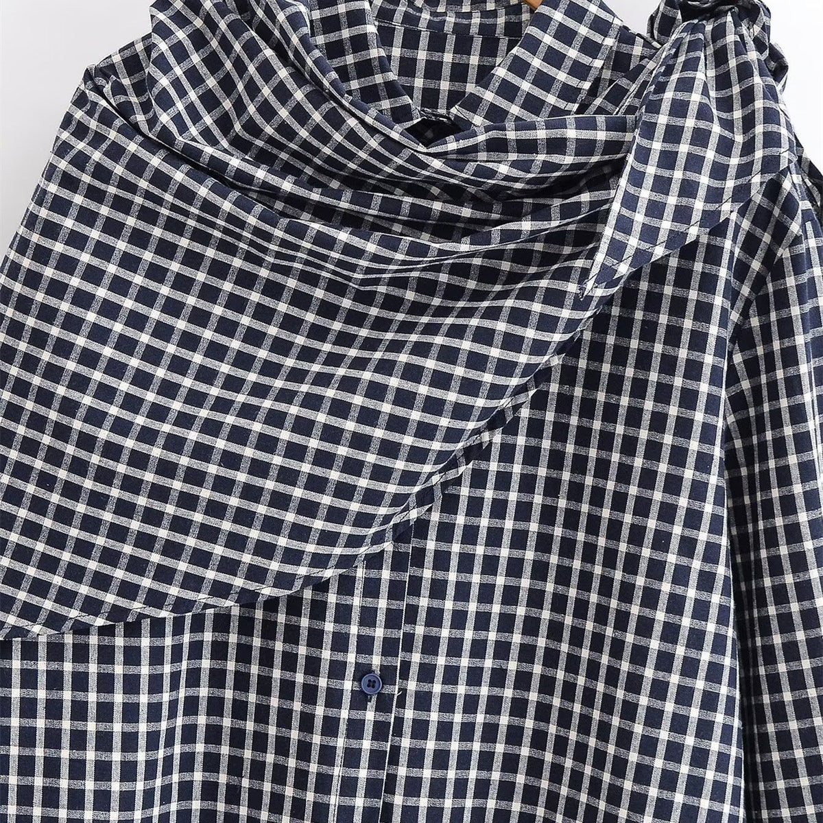 Close-up of the black and white checked shirt's collar and matching knotted scarf.