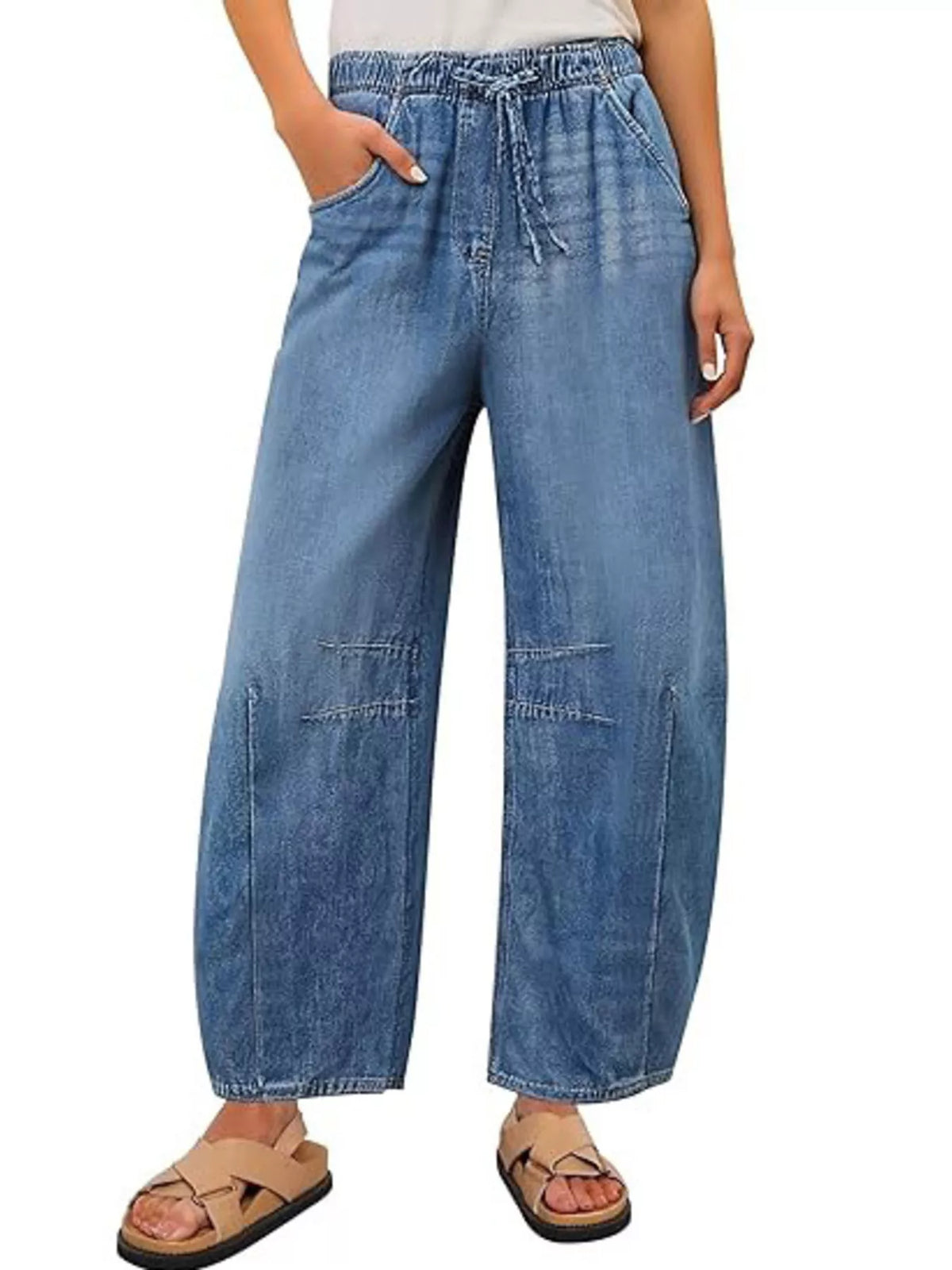 Model wearing light blue wide-leg jeans with a drawstring elastic waist and curved leg seams, front view.