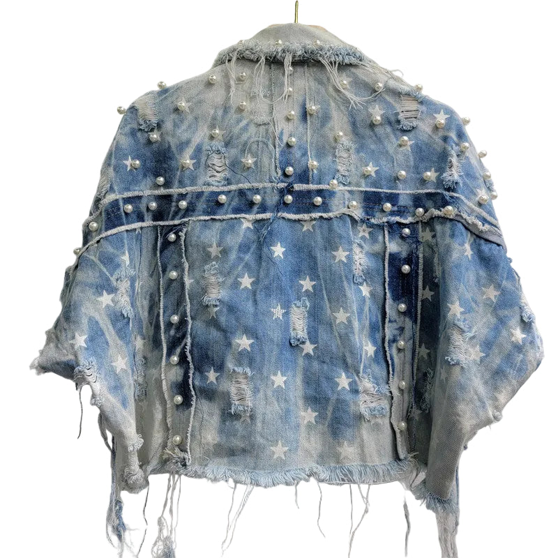 Back view of a cropped distressed blue denim top with white stars, pearl-like studs, and frayed seams.