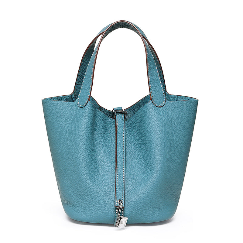 Light blue pebbled bucket bag with twin handles, a front fastening strap, and a silver-tone padlock, front view.