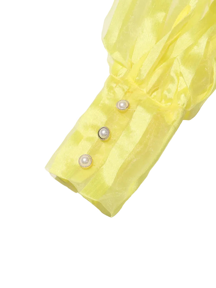 Close-up of the yellow striped blouse's long cuff with three pearl-like buttons.