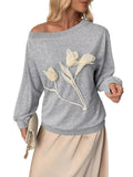 Model wearing a gray boat-neck sweatshirt with cream tulip-shaped floral appliques on the front.