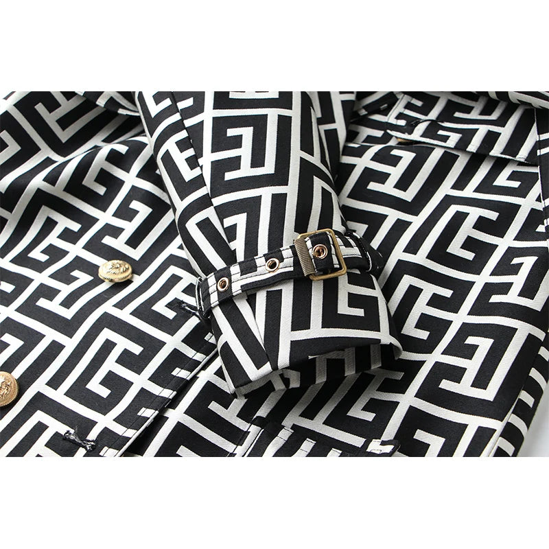 Close-up of the geometric trench coat's sleeve cuff with a gold buckle strap and metal eyelets.
