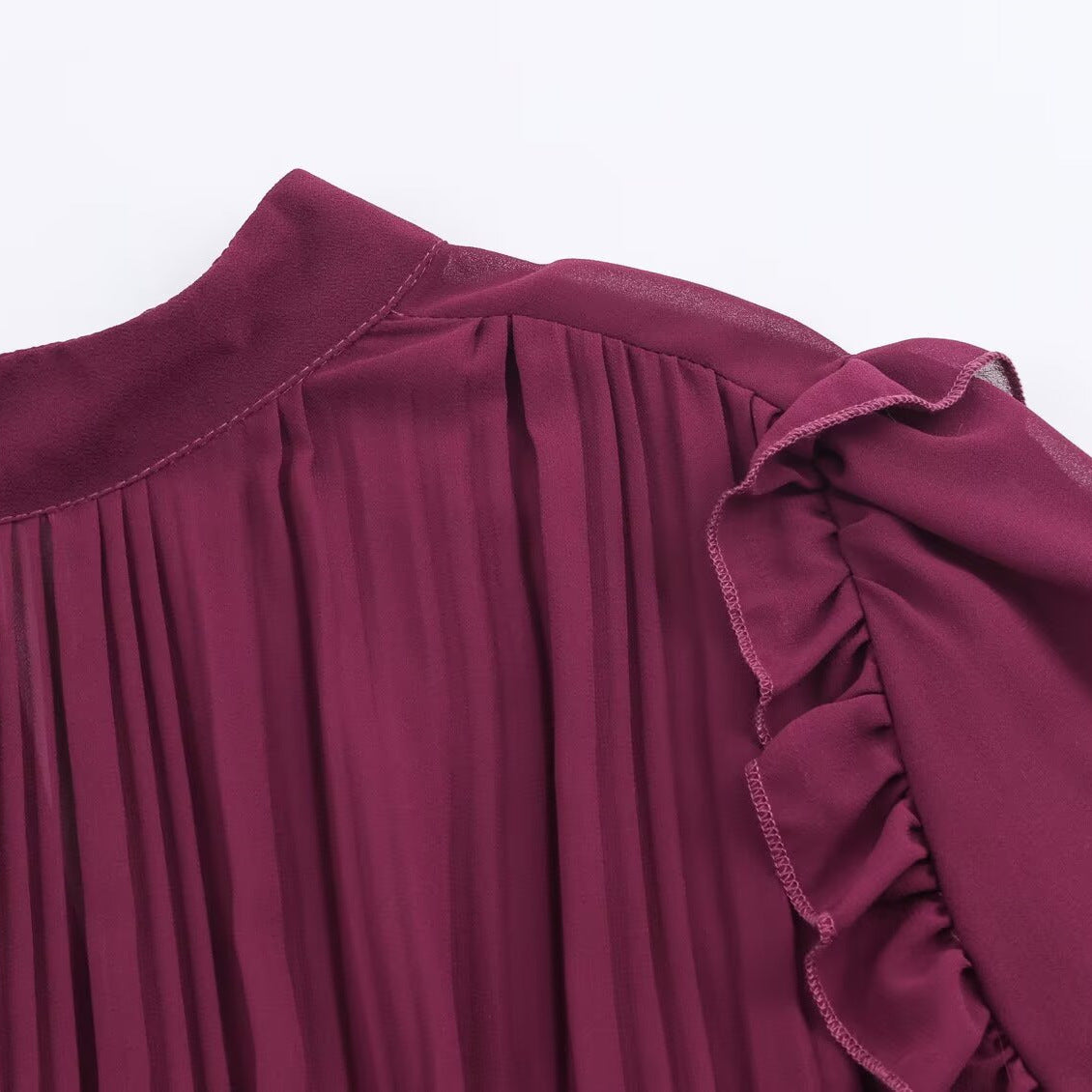 Close-up of the burgundy dress's shoulder ruffle and pleated bodice.