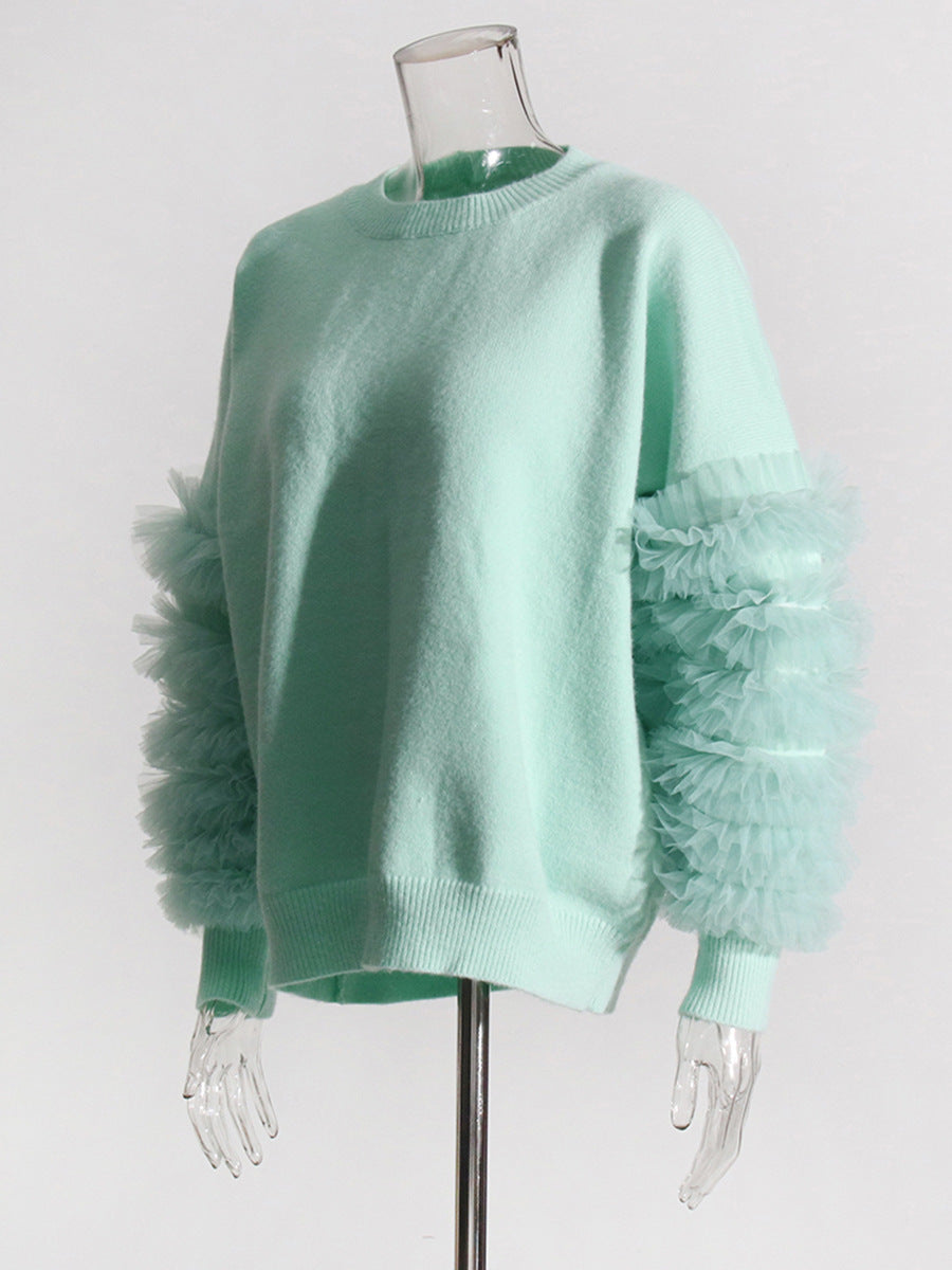 Angled view of a mint green sweater with layered sheer sleeve ruffles on a mannequin.