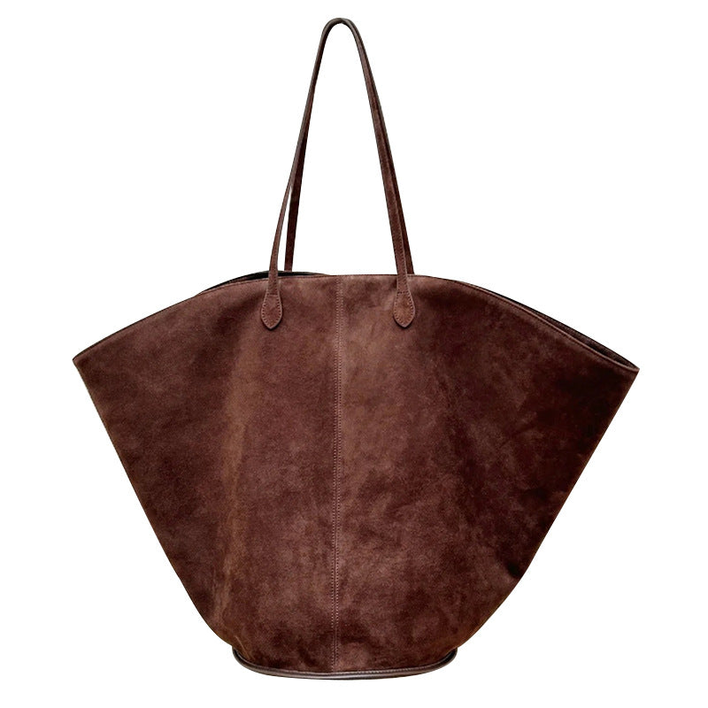 Brown curved tote with long slim shoulder straps, a center seam, and a suede-like finish, front view.