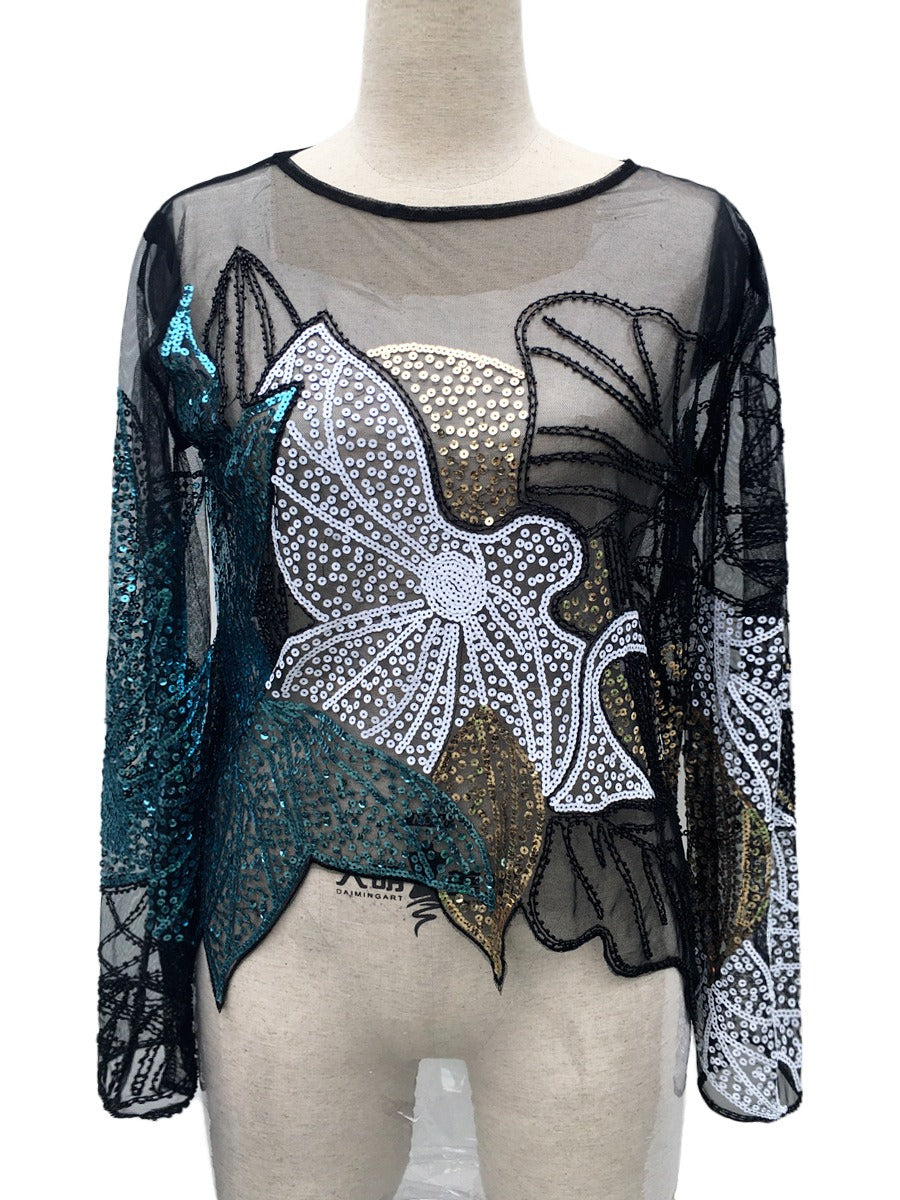 Teal, silver, and gold floral-sequin sheer black top on a mannequin, showing the asymmetric hem.