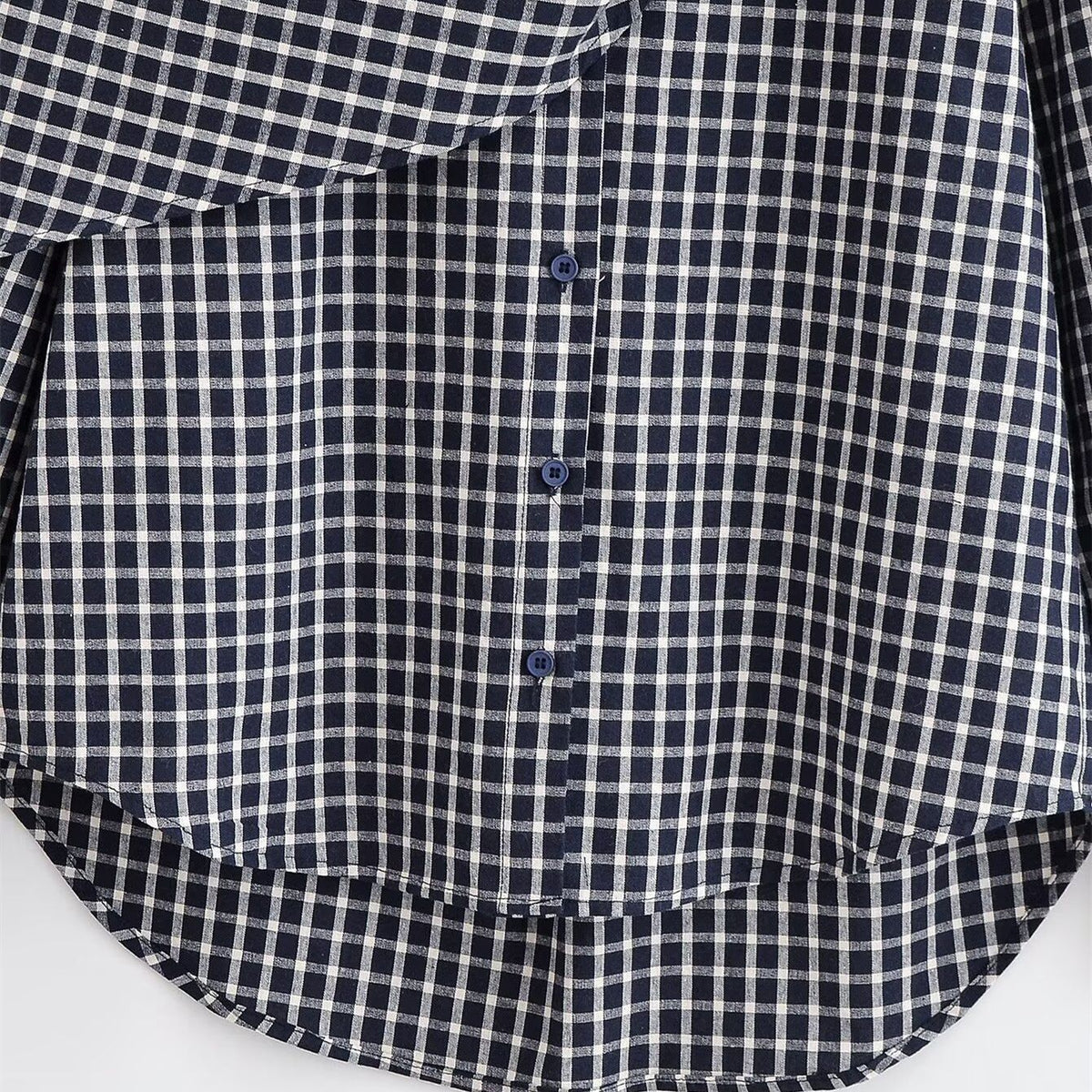 Close-up of the checked shirt's buttons and curved high-low hem.
