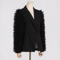 Angled view of a black tailored blazer with layered tulle sleeve ruffles on a mannequin.