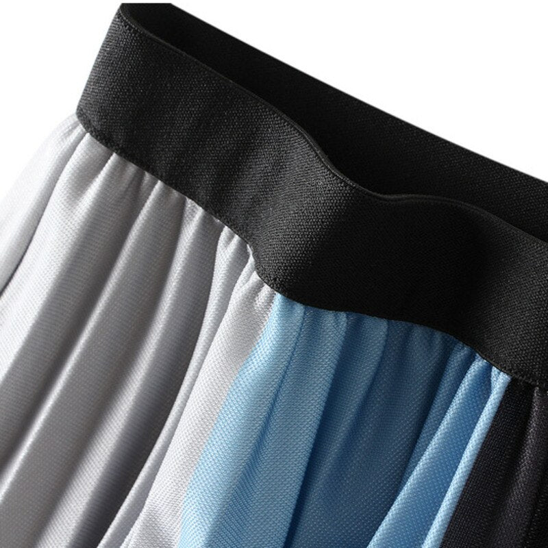 Close-up of the black waistband and gray and blue pleats on a color-block skirt.