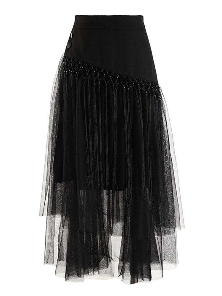 Black layered mesh skirt with an asymmetric buttoned panel and long knotted fringe, front view.