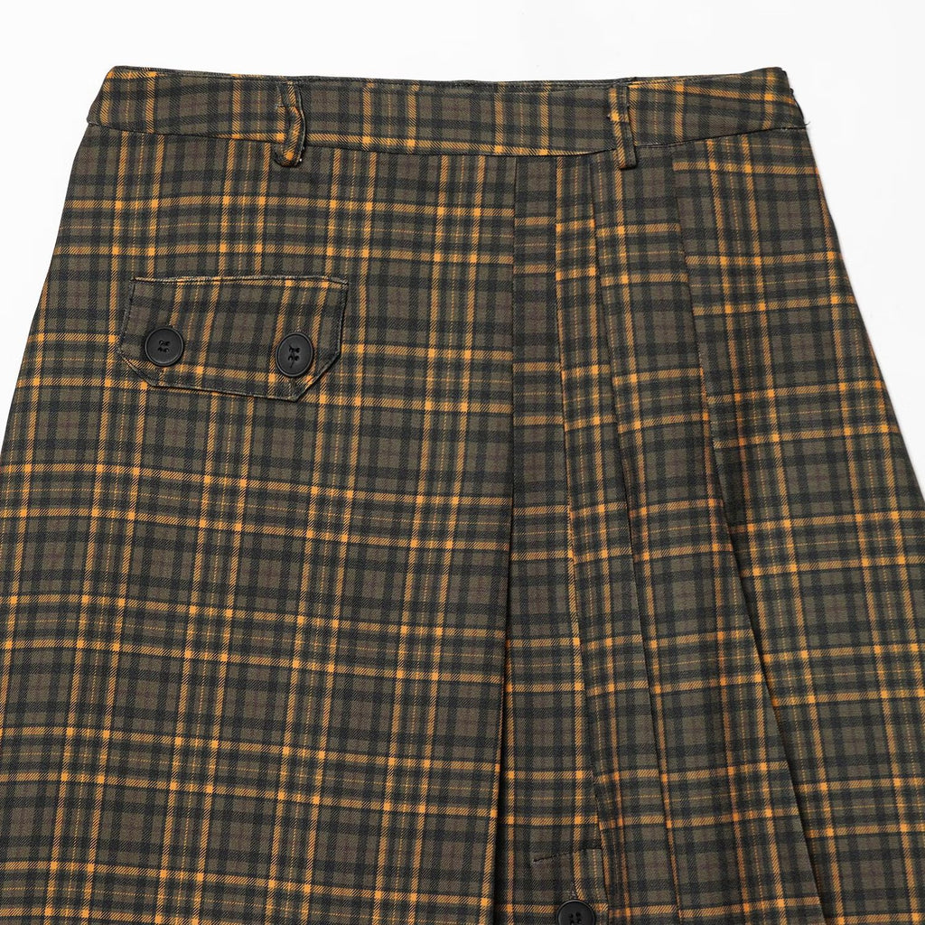 Close-up of the waistband, belt loops, front pleats, and buttoned flap pocket on an olive plaid skirt.