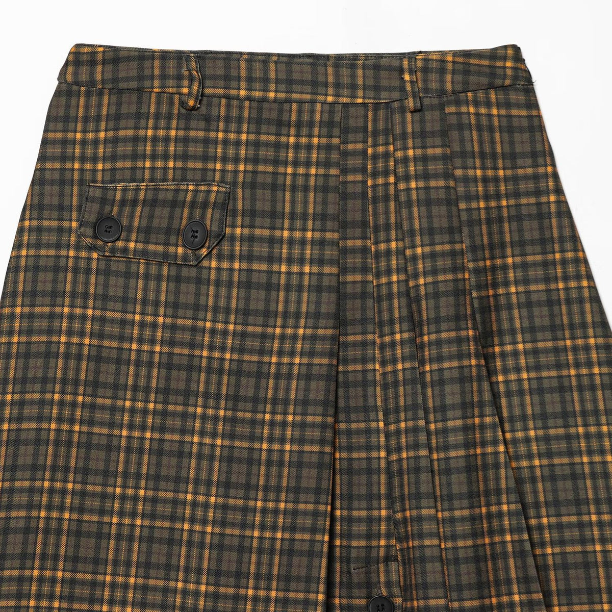 Close-up of the waistband, belt loops, front pleats, and buttoned flap pocket on an olive plaid skirt.