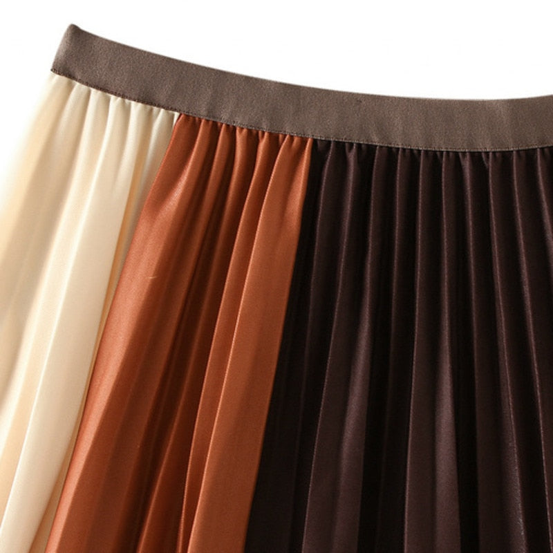 Close-up of the brown waistband and cream, rust, and dark brown pleats on a color-block skirt.