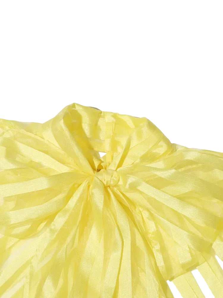 Close-up of the yellow sheer striped blouse's oversized neck bow.