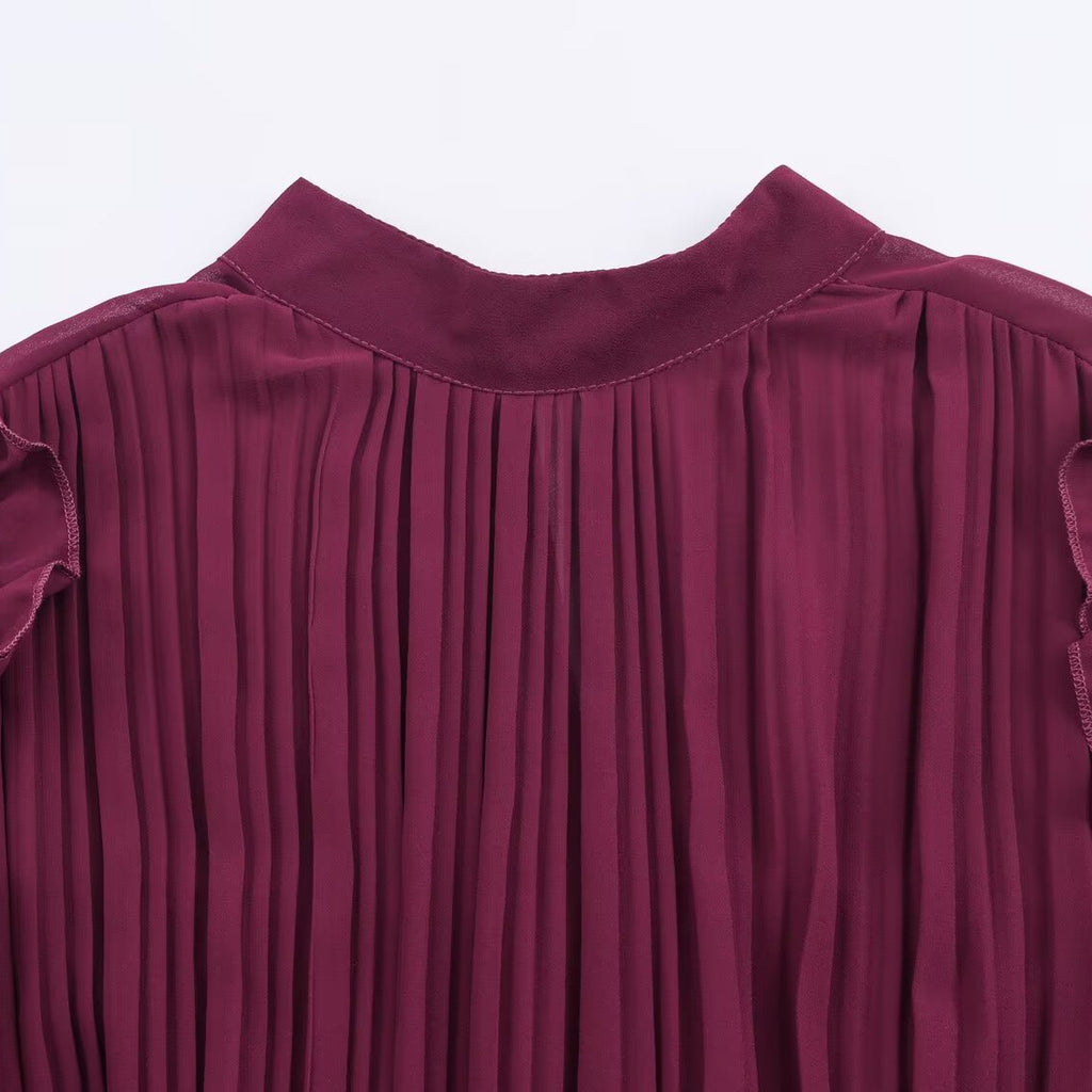 Close-up of the burgundy dress's round neckline and finely pleated bodice.