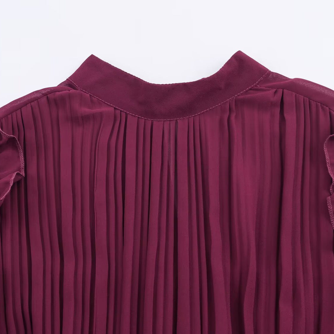 Close-up of the burgundy dress's round neckline and finely pleated bodice.