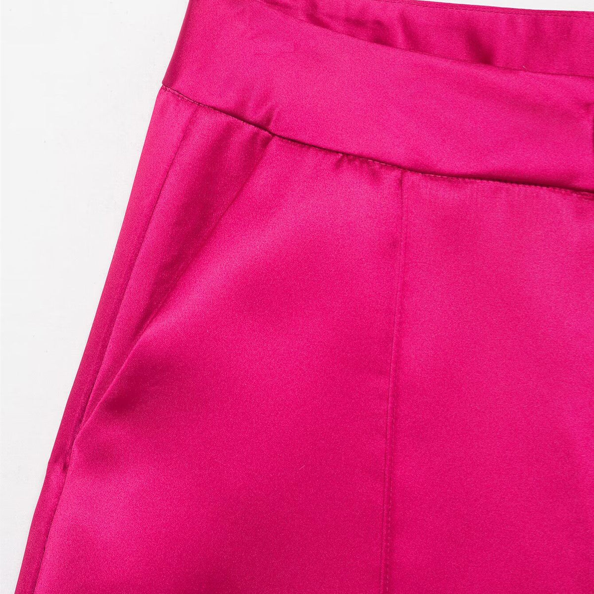 Close-up of the waistband and side pocket on bright pink satin-look pants.