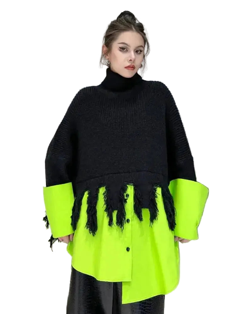 Person wearing a black and neon green sweater with tassels against a neutral background